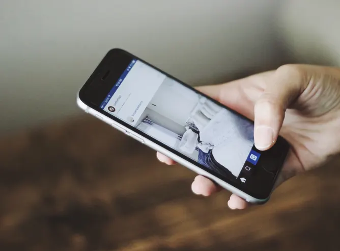 A hand holding a phone open on an Instagram profile